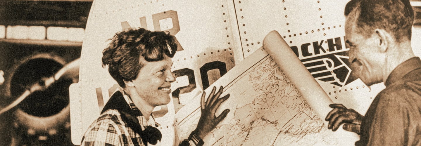 Sepia tone image of Amelia Earhart and her navigator looking at a map to best plan her route