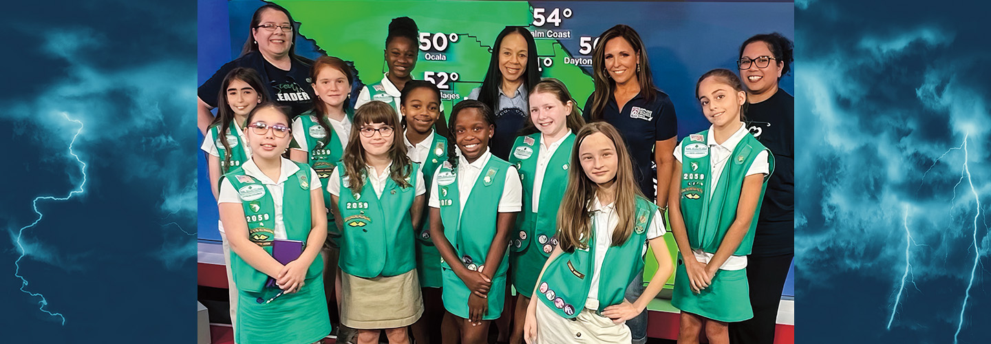 Photo of a troop of girl scouts posing with the Weather Newsreporter