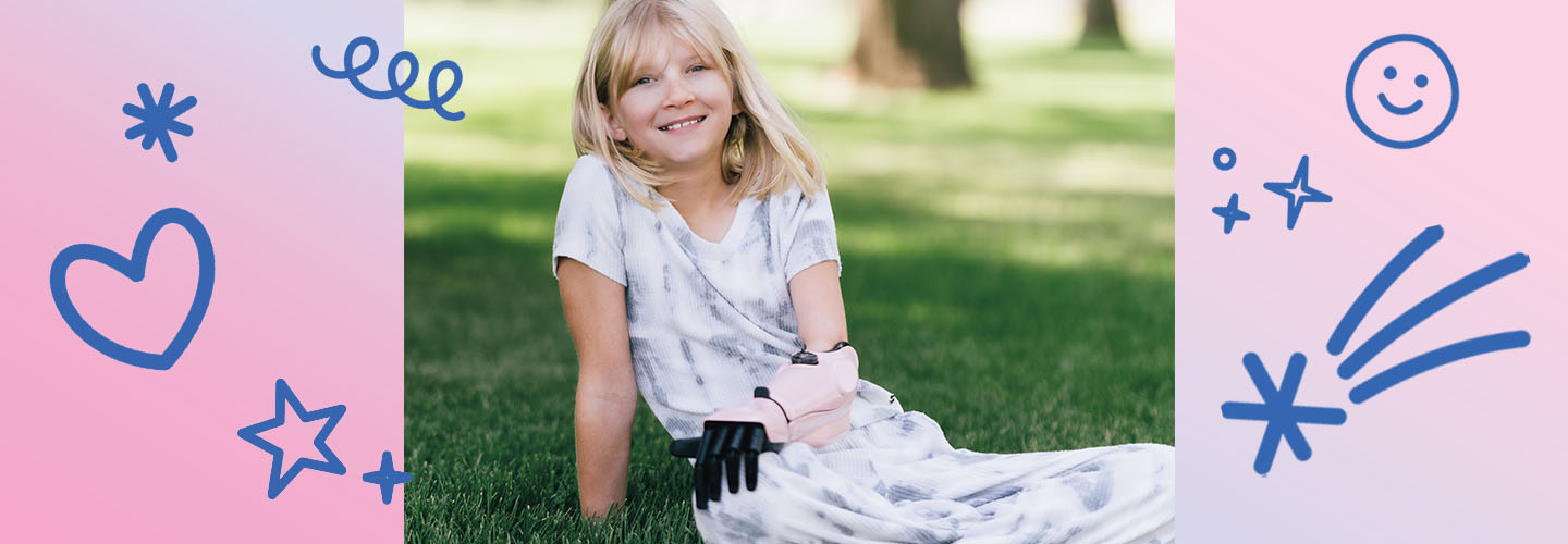 Image of a kid sitting in the park and wearing a prosthetic arm