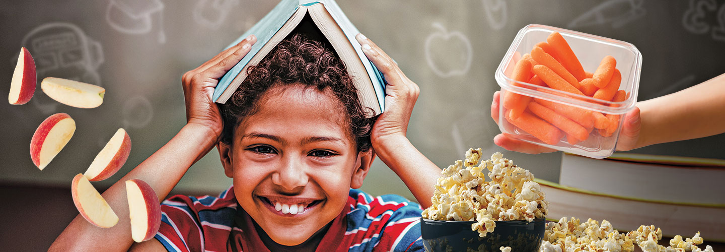 smiling boy with open book on his head being tempted by snacks in front of him